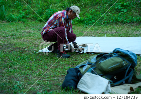 Solo camper setting up a tent, solo camping, senior 127184739