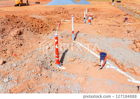 Construction workers are installing plumbing at residential site while earthwork continues 127184888