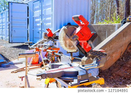 Various power tools are arranged in construction area next to storage units, highlighting an active work environment. 127184891