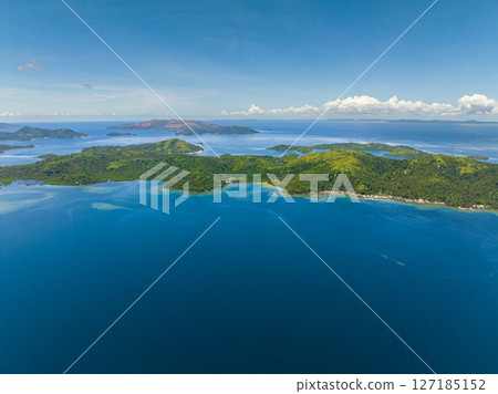 Stunning view of tropical island with small village in coastline.. Blue sea surface and blue skies and clouds. Seascape. Mindanao, Philippines. 127185152