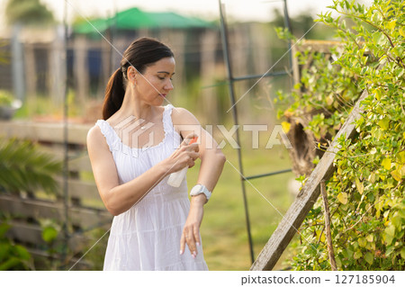 Adult woman applying repellent in cottage garden Adult woman applying repellent in cottage garden 127185904
