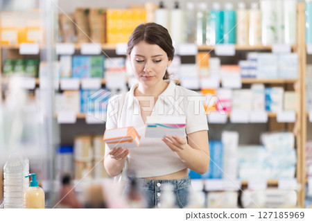 Girl in summer clothes looking for medicine in pharmacy 127185969