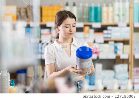 Young woman chooses baby formula at pharmacy Young woman chooses baby formula at pharmacy 127186002