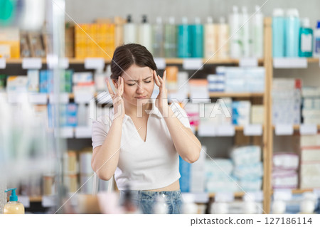 Young woman with headache at pharmacy 127186114