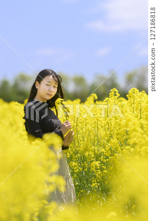 A woman sightseeing in a field of rapeseed flowers in full bloom 127186818