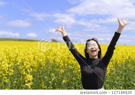 A woman sightseeing in a field of rapeseed flowers in full bloom A woman sightseeing in a field of rapeseed flowers in full bloom 127186820