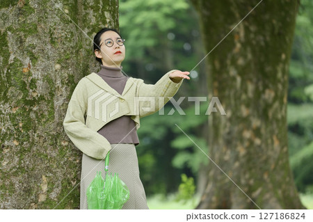 Japanese woman sheltering from the rain under a tree 127186824