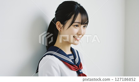 身穿水手服、綁著馬尾、微笑的高中女生靠著牆站著 127186852