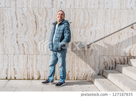 Portrait positive middle-aged man against background marble wall with steps 127187835