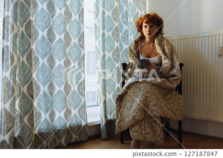 Girl hugging cat, sitting in blanket at home, frozen Girl hugging cat, sitting in blanket at home, frozen 127187847