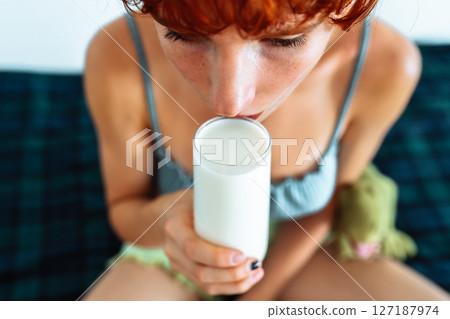 attractive red-haired teenager girl drinks milk attractive red-haired teenager girl drinks milk 127187974