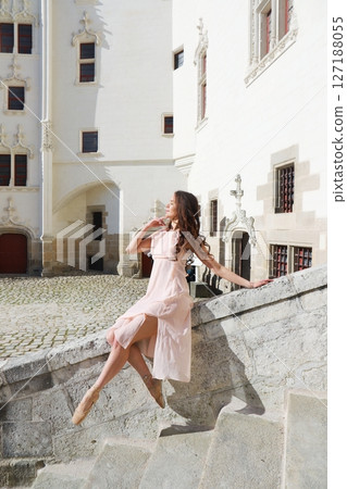 Ballerina sitting en pointe in elegant pose near castle wall in sunlight 127188055