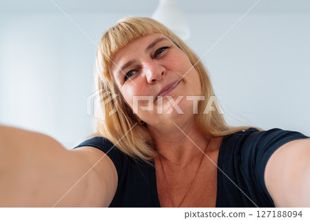 Portrait middle-aged woman, blonde, grimacing in front mirror Portrait middle-aged woman, blonde, grimacing in front mirror 127188094