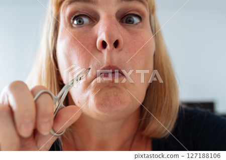 portrait woman plucking facial hair with tweezers 127188106