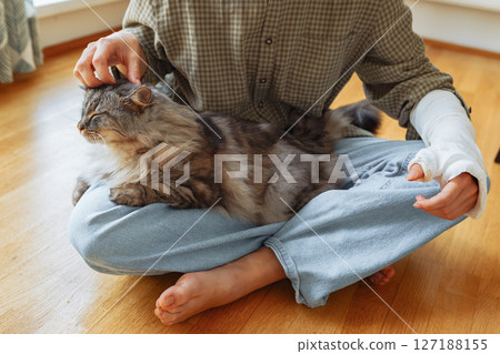 teenager with broken arm in cast and pet cat 127188155