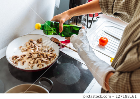 teenage girl, with cast on arm, cook lunch at home 127188161