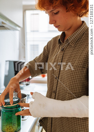 teenage girl, with cast on arm, cook lunch at home teenage girl, with cast on arm, cook lunch at home 127188181