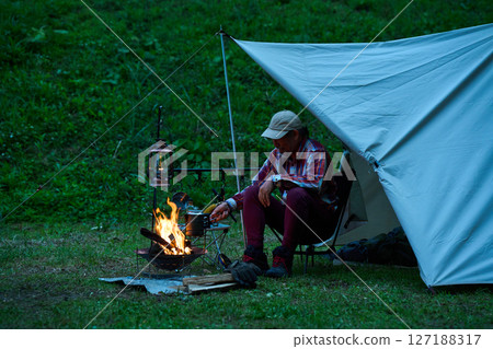 Solo camper boiling coffee, solo camping, senior 127188317
