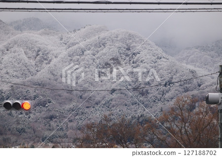 A Japanese landscape with a red light and power lines against the backdrop of a snowy mountain A Japanese landscape with a red light and power lines against the backdrop of a snowy mountain 127188702
