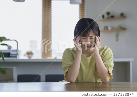 A woman in her 30s holding her head 127188874