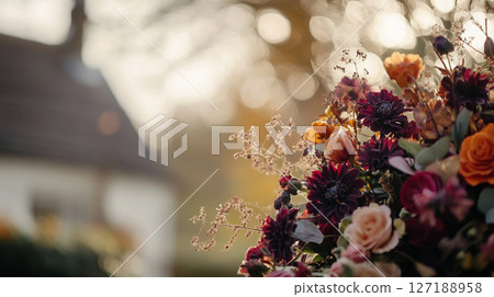 Elegant autumn floral arrangement in warm, muted tones against a bokeh background of golden light. 127188958