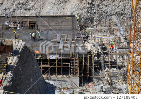 Workers in uniform at construction site build the underground floors of building Workers in uniform at construction site build the underground floors of building 127189403