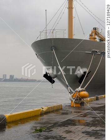 雨天港口的黃色繫泊柱和停泊船隻 127189429