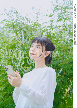 A refreshing woman in her 30s outdoors operating a smartphone 127190257