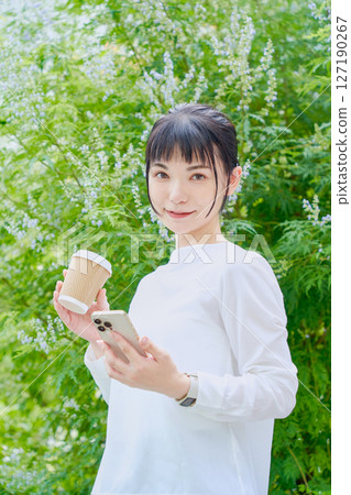 A refreshing woman in her 30s outdoors operating a smartphone 127190267