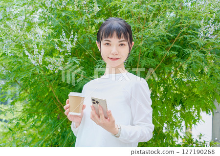A refreshing woman in her 30s outdoors operating a smartphone 127190268