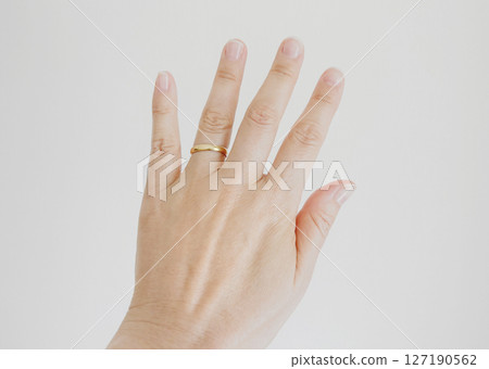 A woman wearing a ring on her left ring finger 127190562