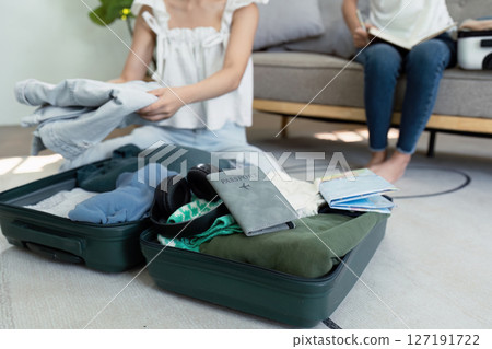 A woman is sitting on the floor with her luggage open 127191722
