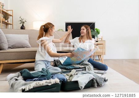 Young friends are happy after planning traveling together for the holiday. Two women are friends packing suitcases for holiday 127191885