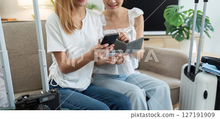 Happy young woman with credit card booking vacation at travel agency or making hotel reservation online 127191909