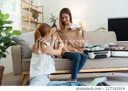 Two women friends packing suitcases for holiday. happily choose clothes together for the holiday Two women friends packing suitcases for holiday. happily choose clothes together for the holiday 127191914