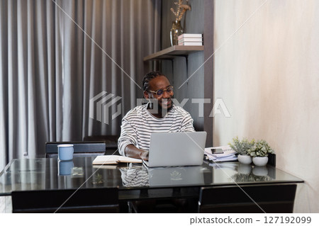 Young African American business man working with laptop and document on desk at home. work from home concept Young African American business man working with laptop and document on desk at home. work from home concept 127192099