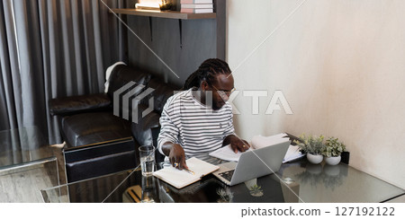 Young African American business man working with laptop and document on desk at home. work from home concept Young African American business man working with laptop and document on desk at home. work from home concept 127192122