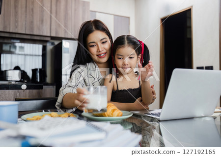 Business woman working at home. Businessman working on laptop and feeding child 127192165