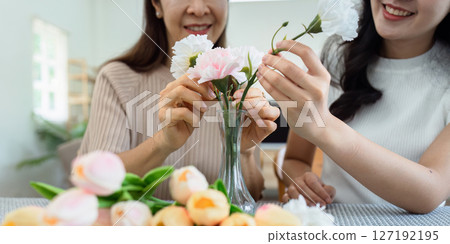 Mother and daughter arrange flower together at home on the weekend, family activities, mother and daughter do activities together on Mother's Day 127192195