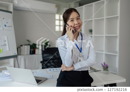Business woman talking on mobile about meeting at meeting room, looking at camera Business woman talking on mobile about meeting at meeting room, looking at camera 127192216
