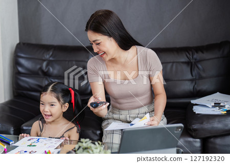 Businessman working at home. working woman talk on mobile and working on tablet and take care of her daughter during summer Businessman working at home. working woman talk on mobile and working on tablet and take care of her daughter during summer 127192320