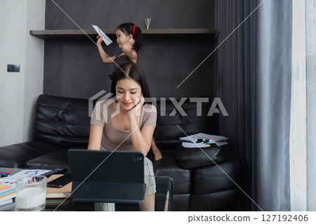 business woman work from home and take care of her child while working, doing activities with her child while working 127192406