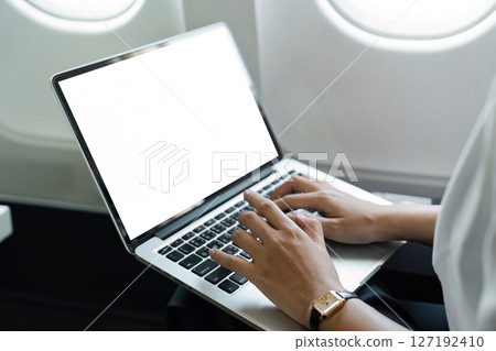 Business travel: Professional woman typing on a laptop in flight 127192410