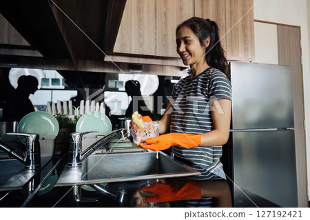 housewife cleans the house and washes the dishes at the sink. Cleaning home concept housewife cleans the house and washes the dishes at the sink. Cleaning home concept 127192421
