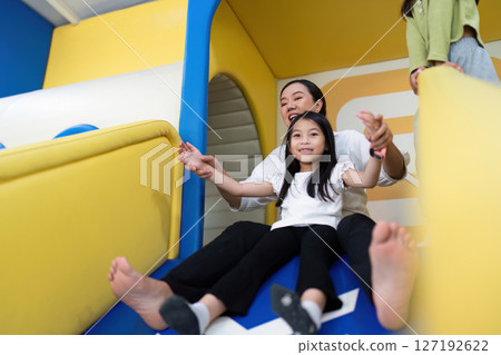 Joyful Sliding. A mother and daughter having fun on a colorful slide. Joyful Sliding. A mother and daughter having fun on a colorful slide. 127192622