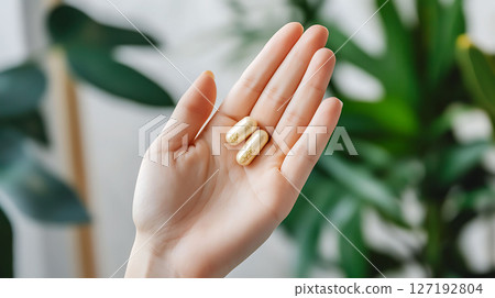 closeup of hand holding plant-based medicine capsule 127192804
