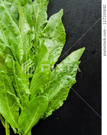 Pile of fresh green spinach sorrel leaves on the wooden table background, top view bunch of greens on the table with water drops. Pile of fresh green spinach sorrel leaves on the wooden table background, top view bunch of greens on the table with water drops. 127193692