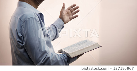 A man with a bible preaches 127193967