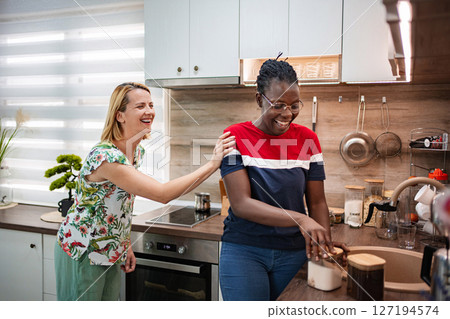 Two friends enjoy a lively moment in a stylish kitchen Two friends enjoy a lively moment in a stylish kitchen 127194574