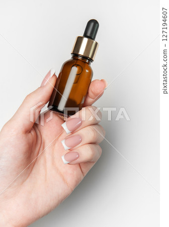 Woman hand holding cosmetic dropper bottle on white background Woman hand holding cosmetic dropper bottle on white background 127194607